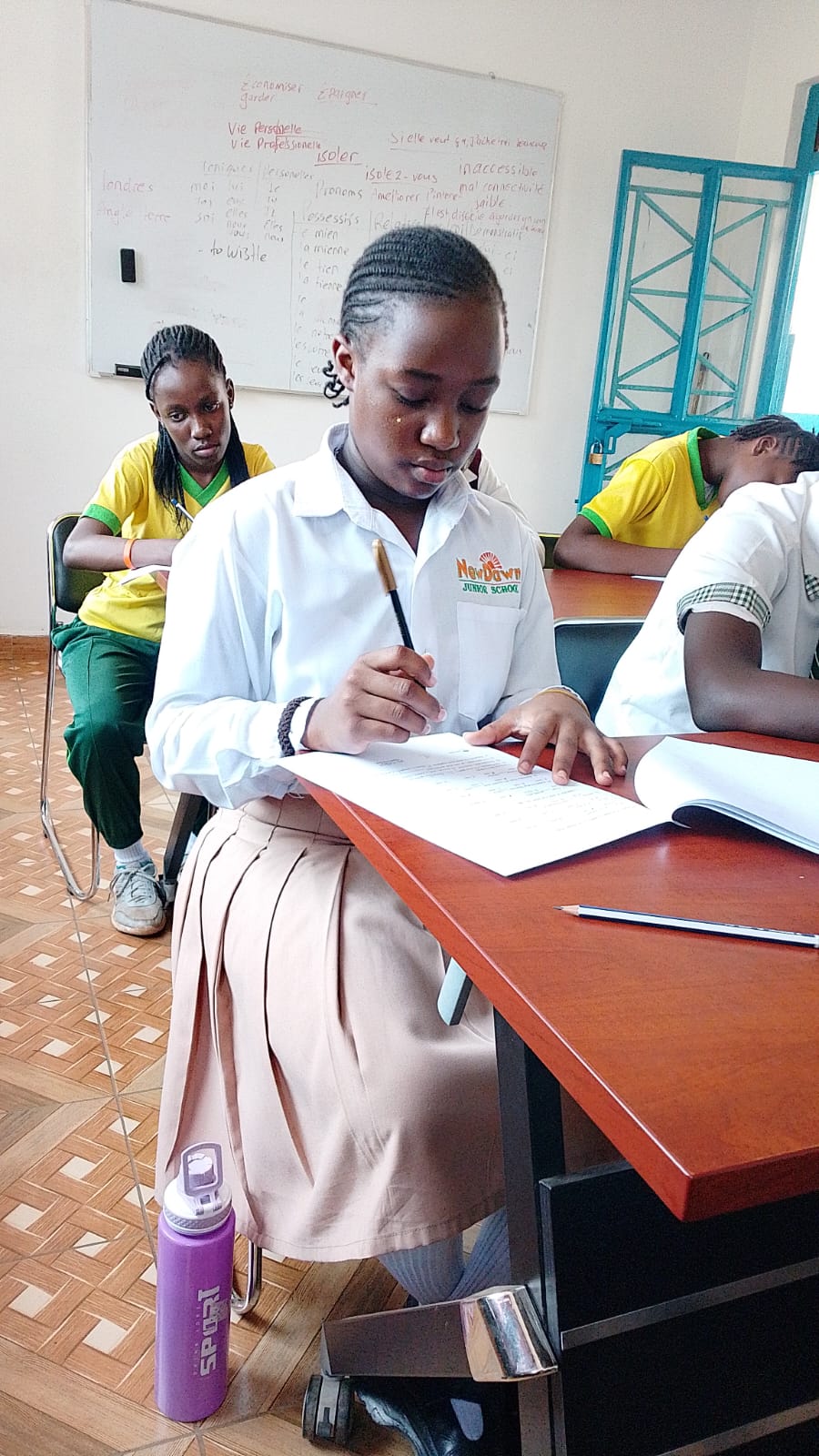 A NewDawn learner writing at a desk during the trip